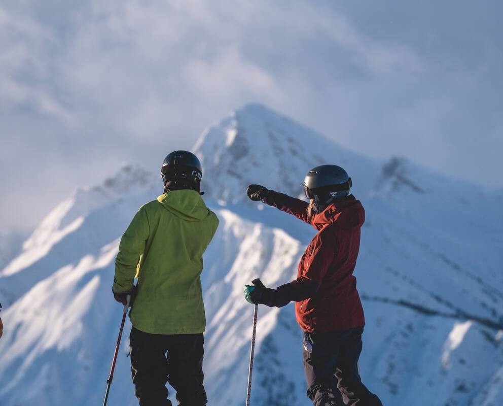 A trio of skiers and snowboarders taking in the view from a mountaintop at Kicking Horse Mountain Resort.