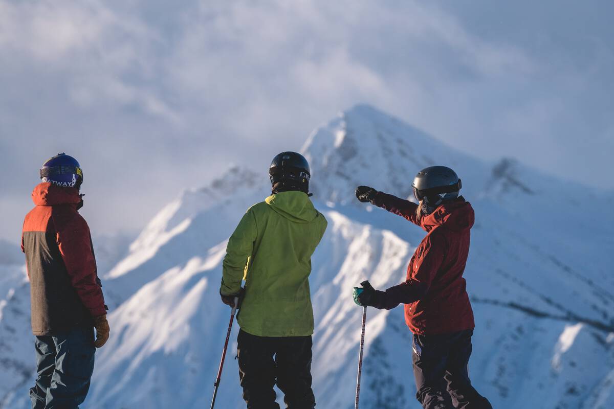 A trio of skiers and snowboarders taking in the view from a mountaintop at Kicking Horse Mountain Resort.