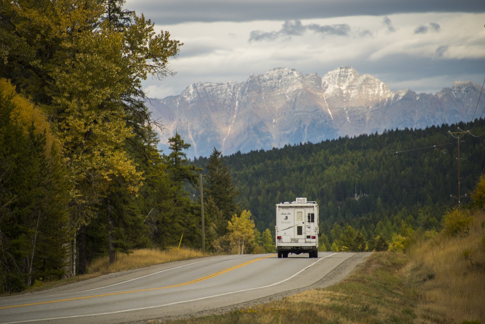 An RV drives away down a highway towards the mountain