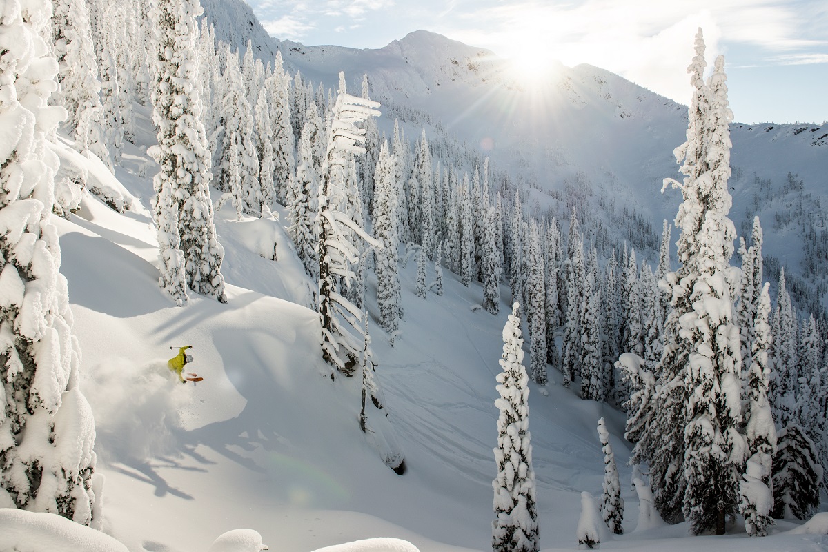 One skier in a bright yellow jacket carves through the deep snow