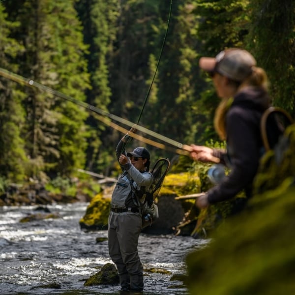 Two women standing in the river fly fishing.