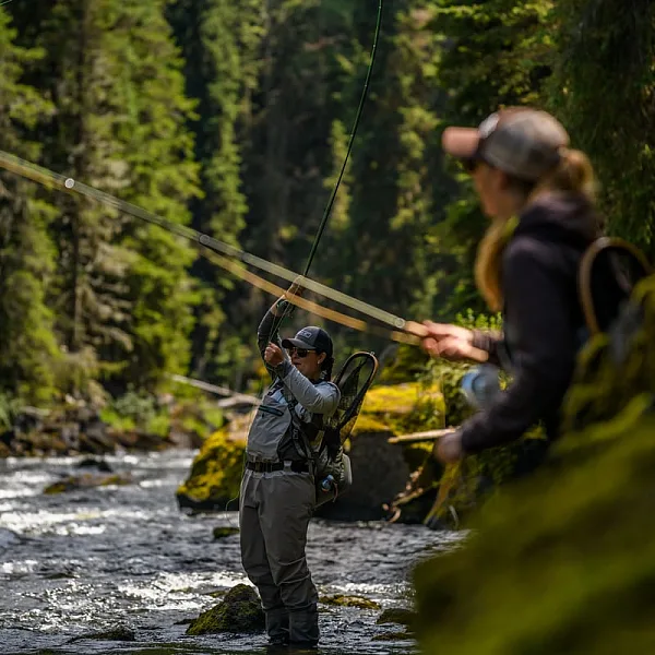 Two women standing in the river fly fishing.