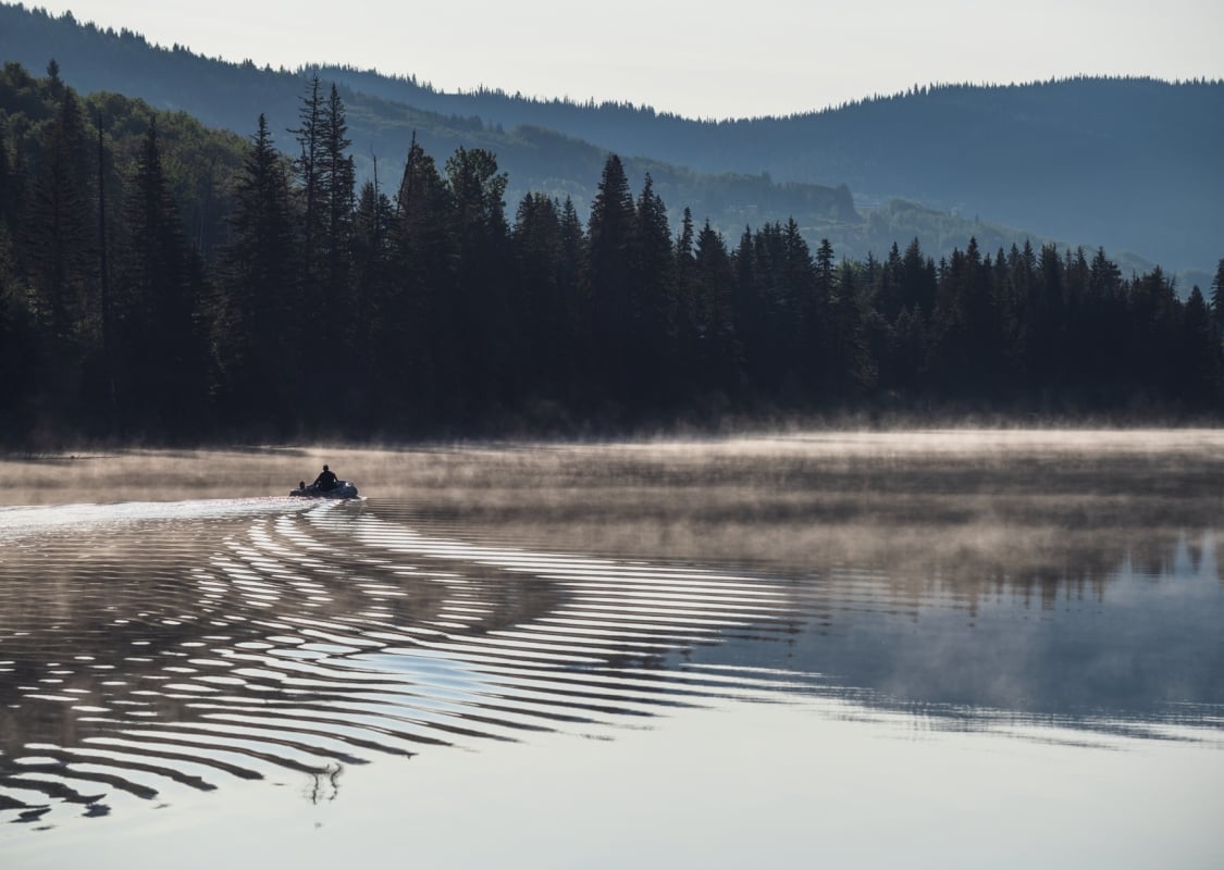 A boat heads out fishing on a misty morning on Lac des Roches