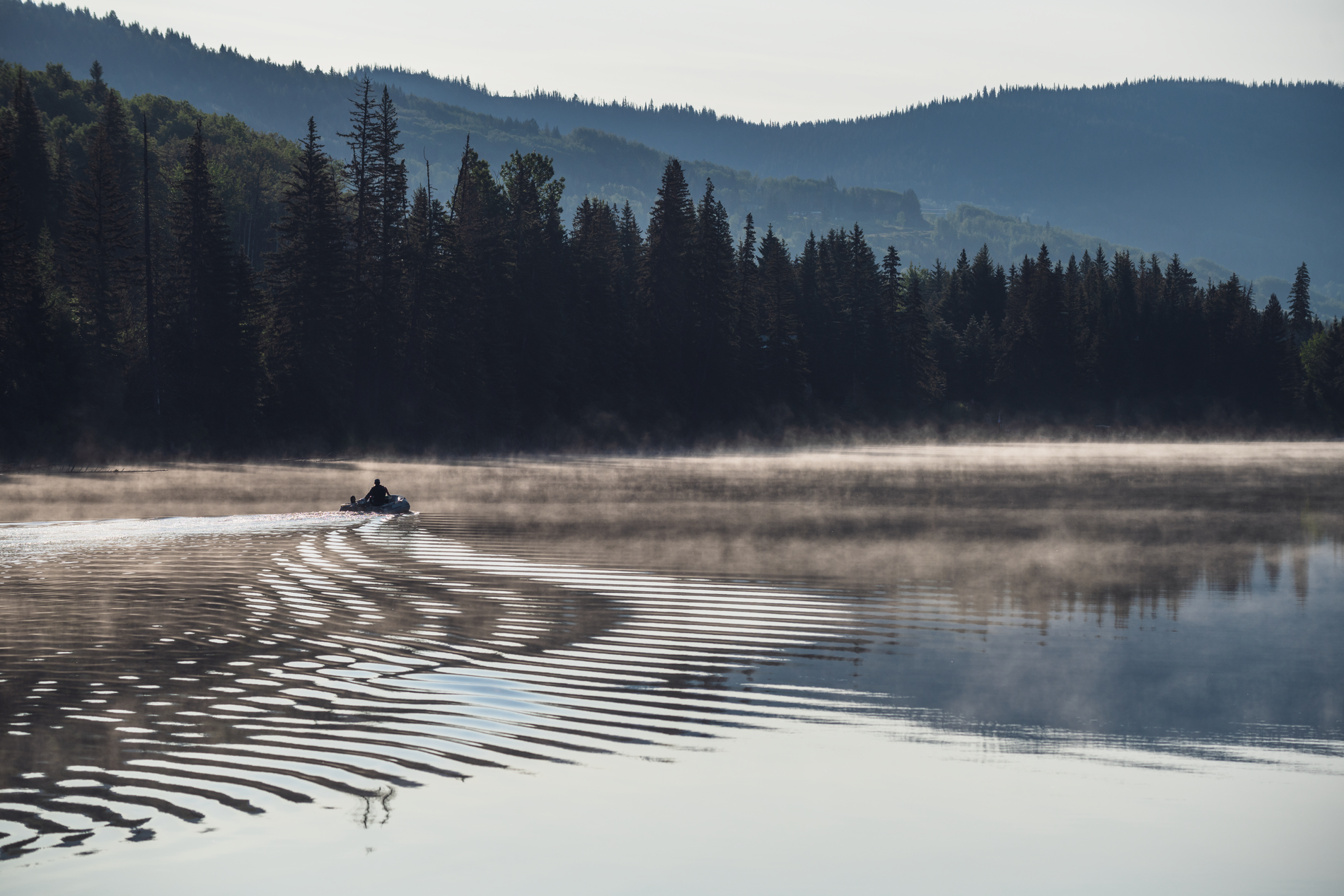 A boat heads out fishing on a misty morning on Lac des Roches