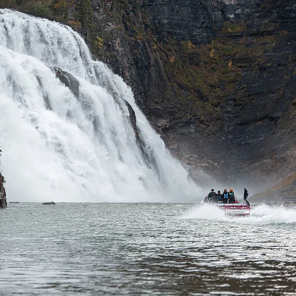 A jet boat approaches a cascading waterfall that towers over 70 metres high.