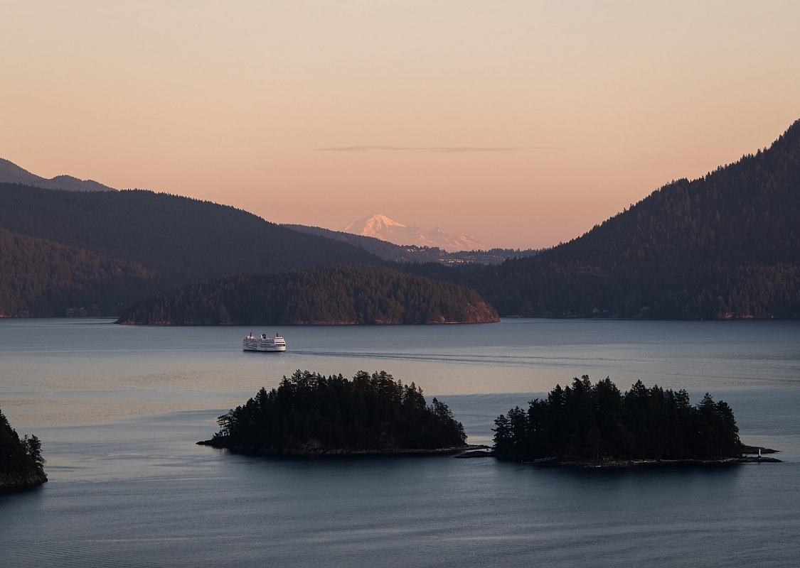 Luftaufnahme einer BC Ferry, die bei Sonnenuntergang an zwei kleinen Inseln vorbeifährt