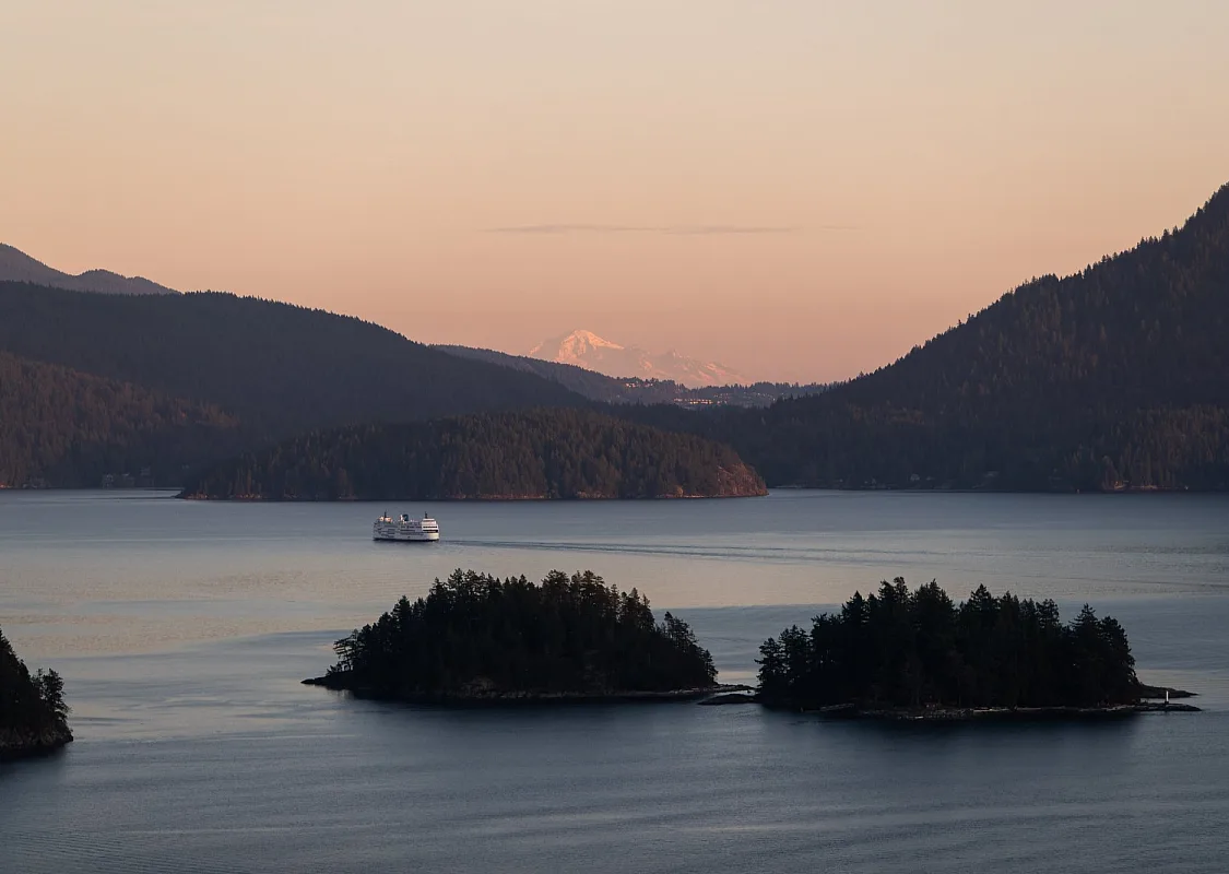 Luftaufnahme einer BC Ferry, die bei Sonnenuntergang an zwei kleinen Inseln vorbeifährt