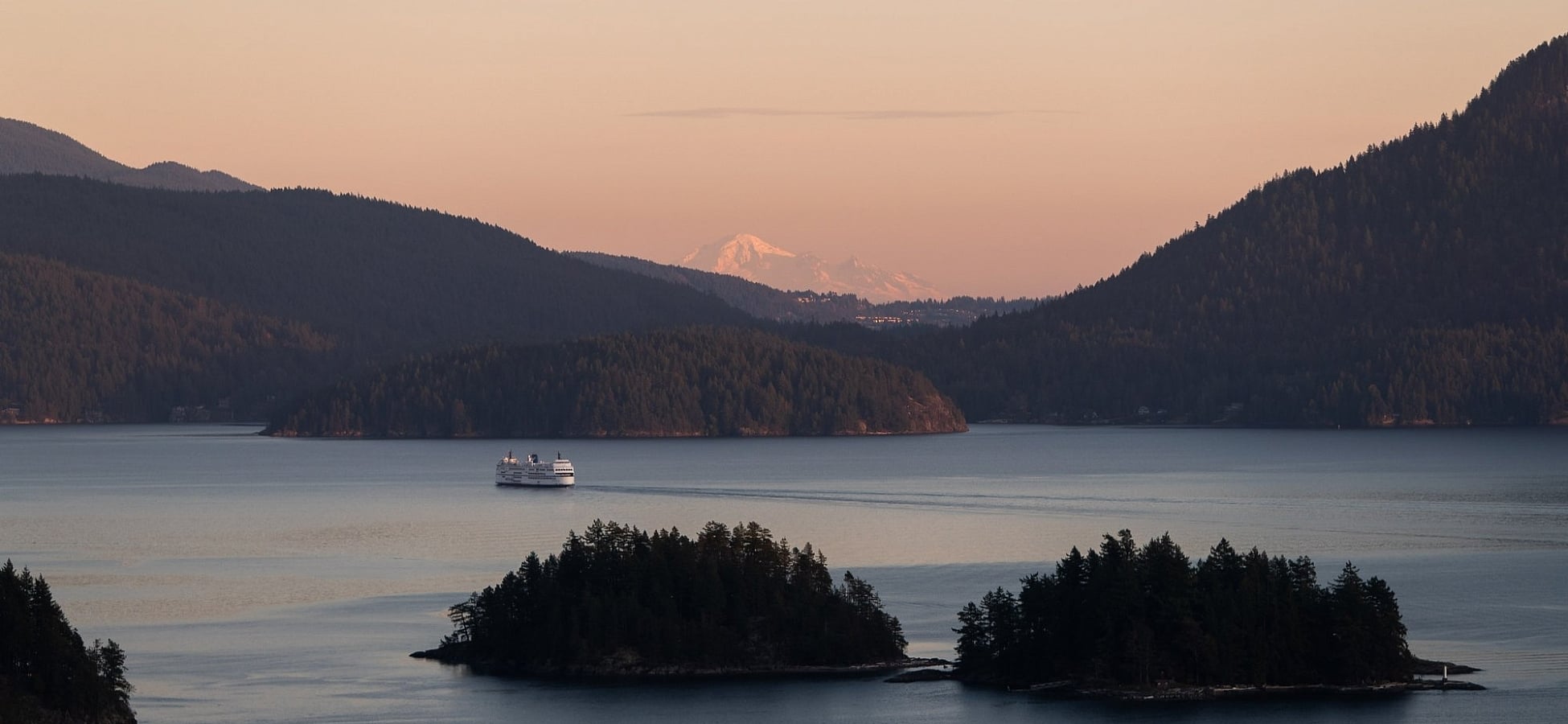 Vista aérea de un BC Ferry navegando junto a dos pequeñas islas al atardecer
