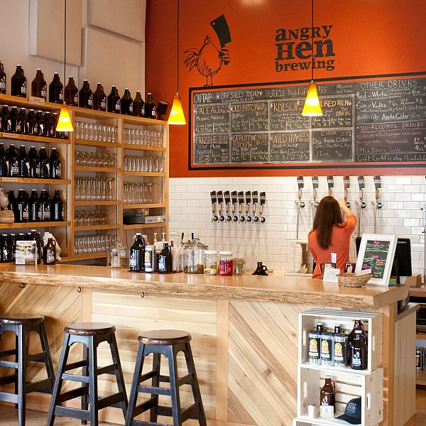 A woman pours a beer from a tap inside Angry Hen Brewing