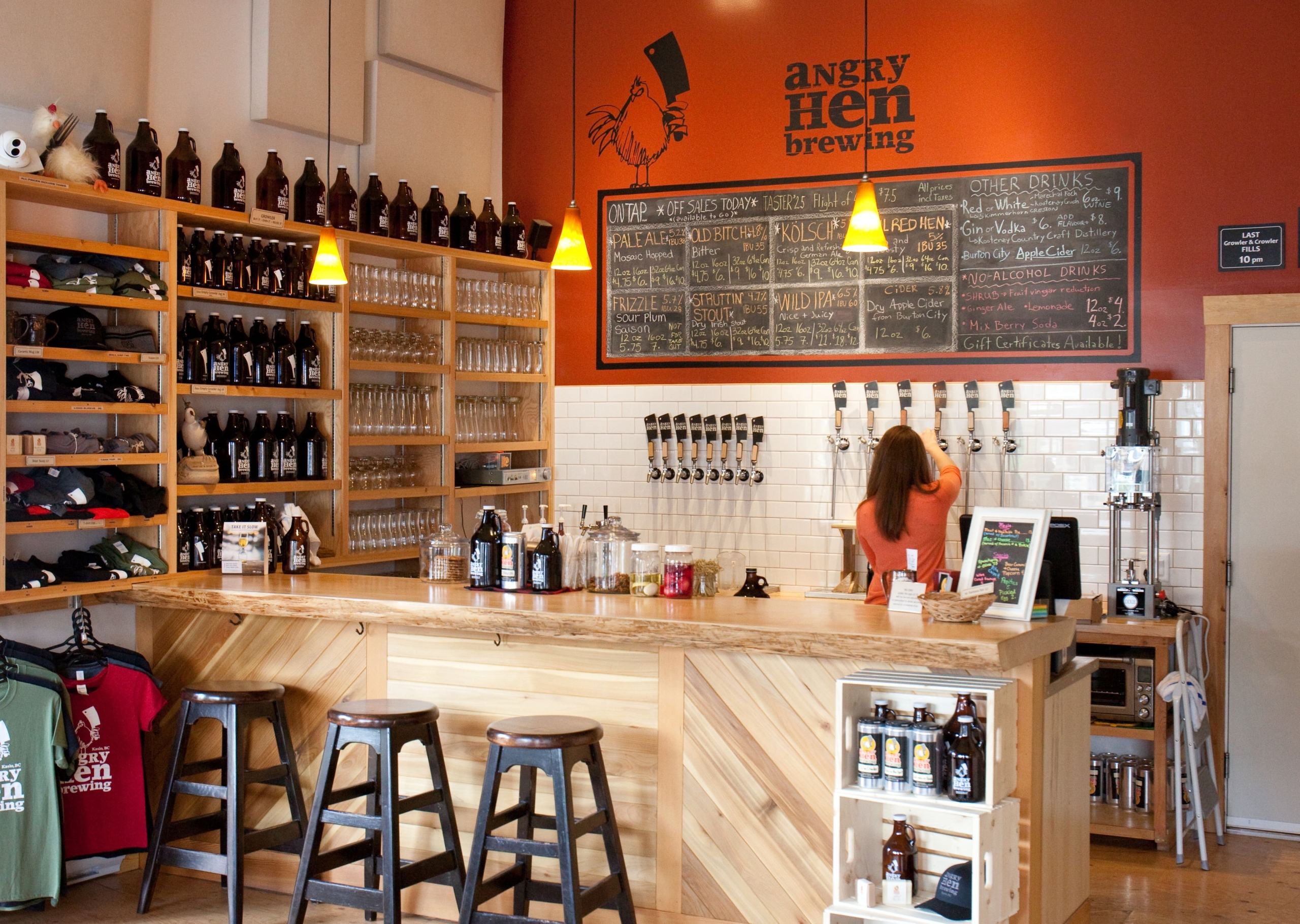 A woman pours a beer from a tap inside Angry Hen Brewing