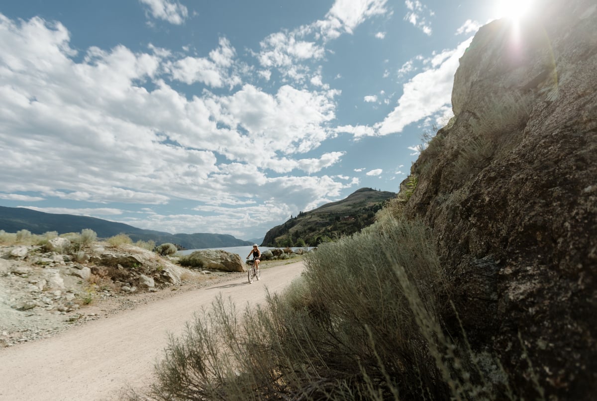 A cyclist on the Okanagan Rail Trail on a bright sunny day.