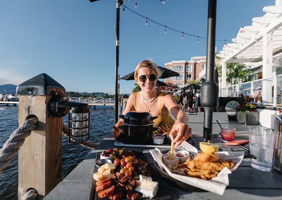 A woman tips her french fry into sauce at an outdoor patio at the Hotel Eldorado. She is sitting in the sun and looking towards the other diner (not seen in the photograph).