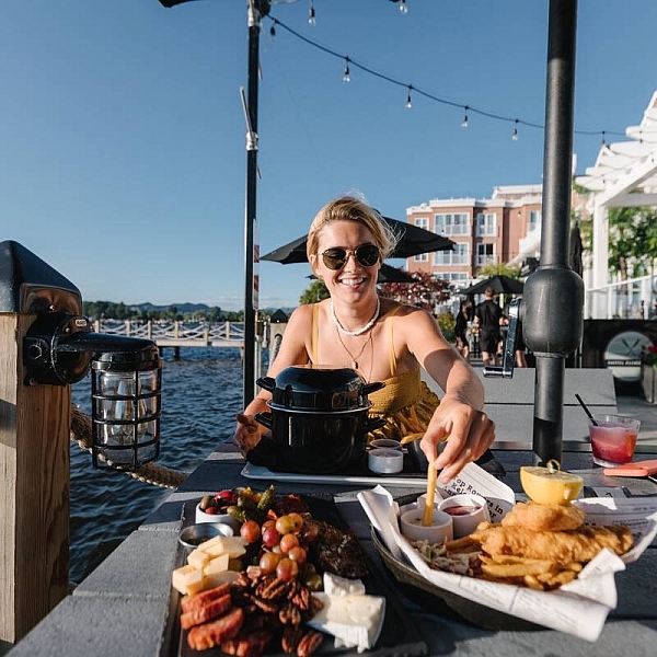 A woman tips her french fry into sauce at an outdoor patio at the Hotel Eldorado. She is sitting in the sun and looking towards the other diner (not seen in the photograph).
