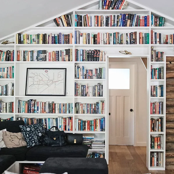 A cabin with a bookshelf wall at the Sunwolf Cabins. A couch with throw pillows in front.