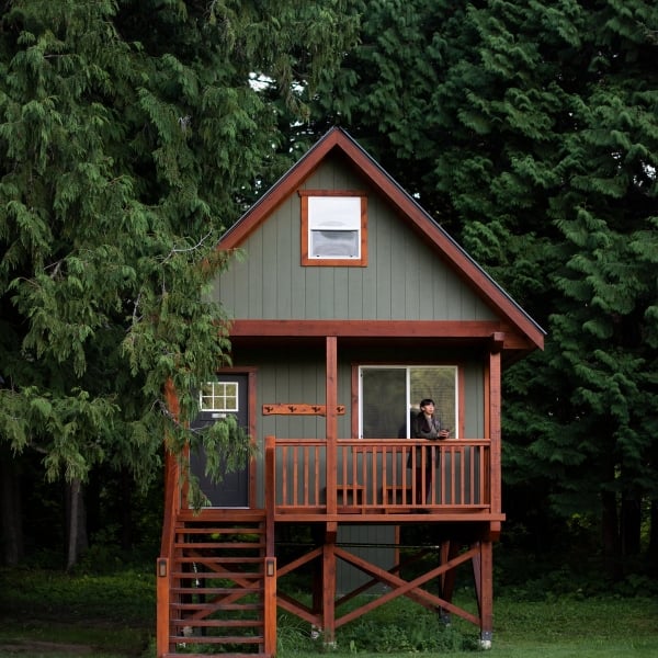 A green cabin with food frame in the forest at Hidden Acres Treehouse Resort