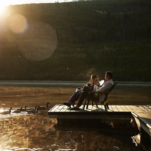 Dos personas sentadas en un muelle al atardecer en Chuta Lake Lodge.
