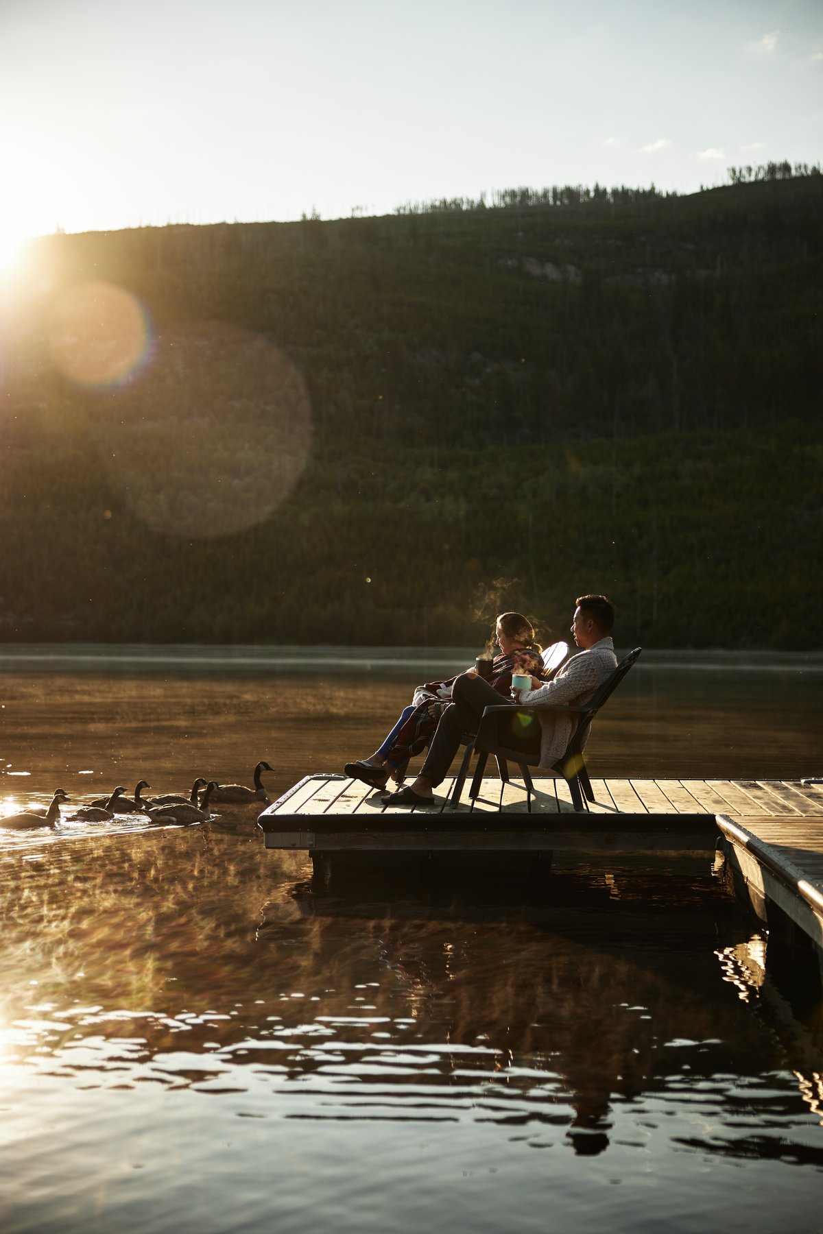 Two people sit on a dock at sunset at Chuta Lake Lodge