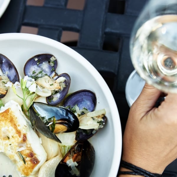Ein Teller mit Muscheln und anderen Meeresfrüchten und ein Glas Wein auf einem Tisch.