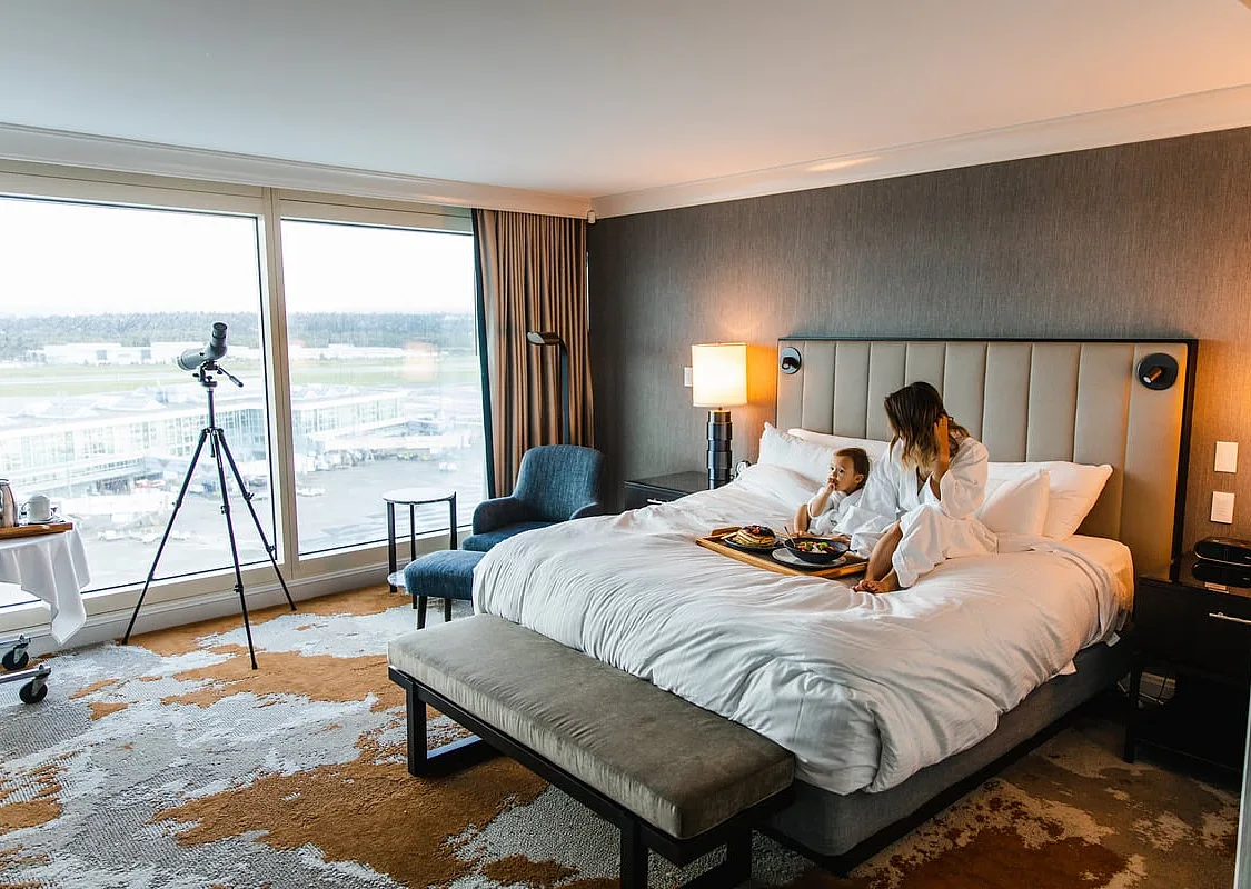 Eine Mutter und ihr Kind sitzen in Bademänteln auf einem Bett in einem Hotel