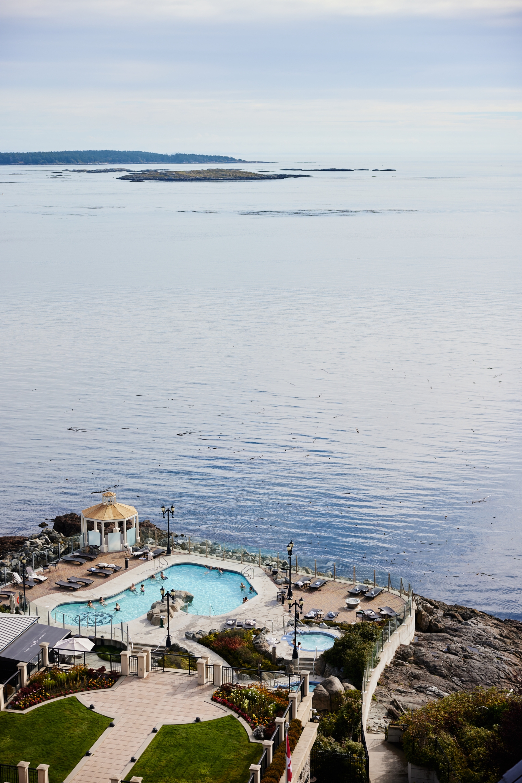 A aerial view of the hot tub and pools at the Oak Bay Beach Hotel as they look out onto the ocean in front.