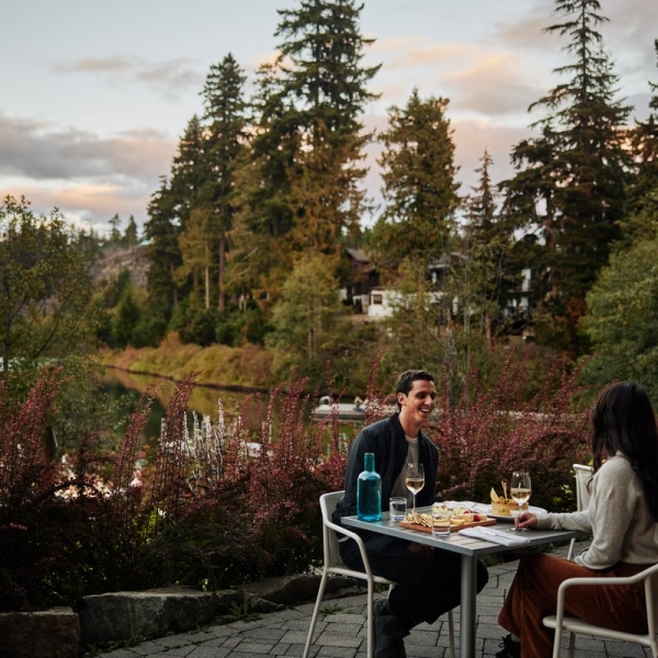 Two people dine on a patio at Nita Lake Lodge