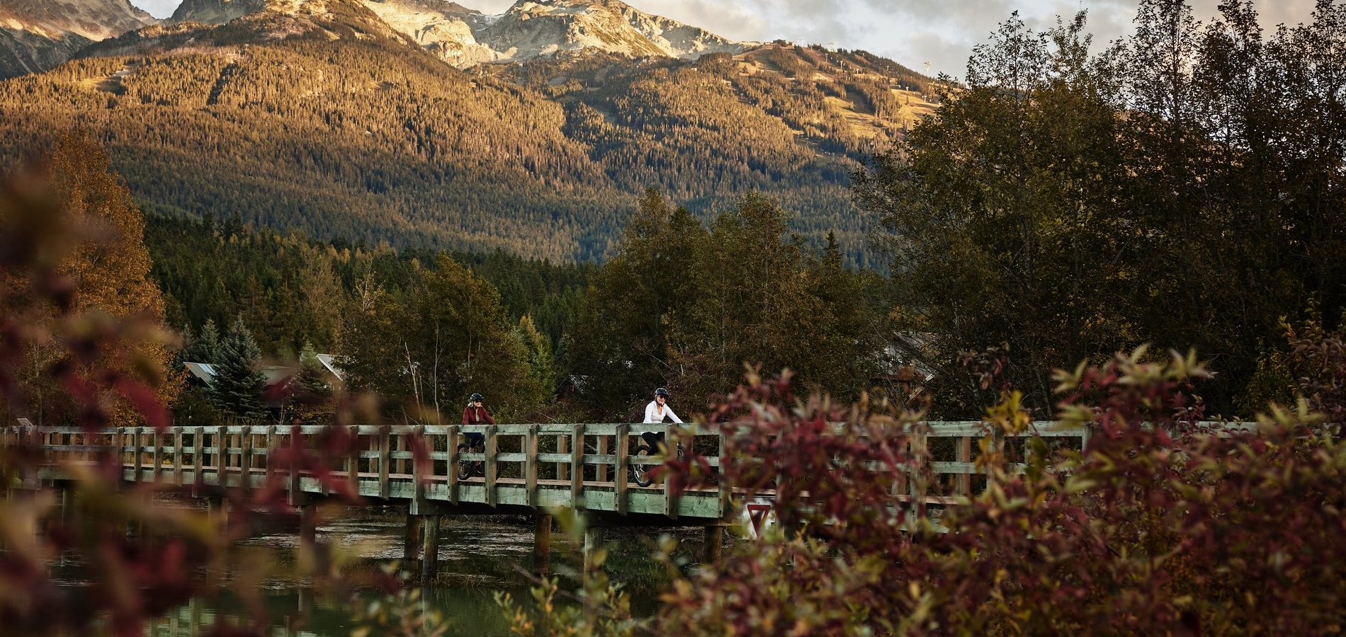 Two women cycle across a bridge at Green Lake, Whistler