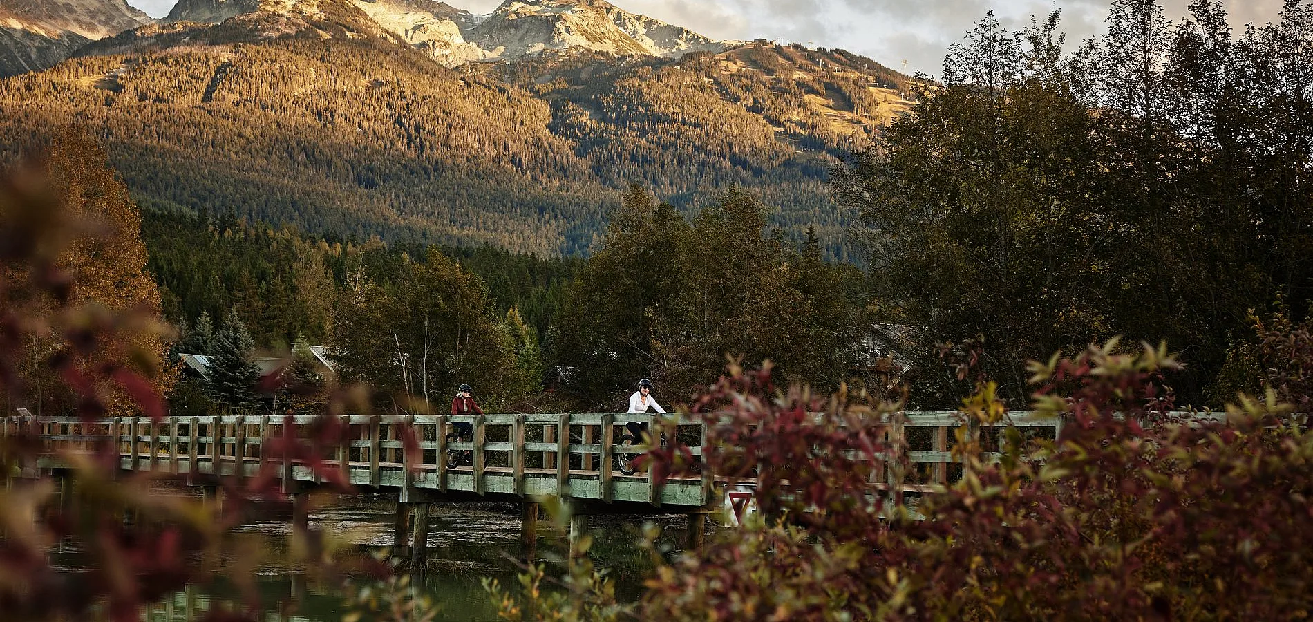 Zwei Frauen radeln über eine Brücke am Green Lake, Whistler.