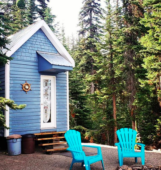 A small blue cabin with two blue chairs out front at Oyama Lake Eco Lodge