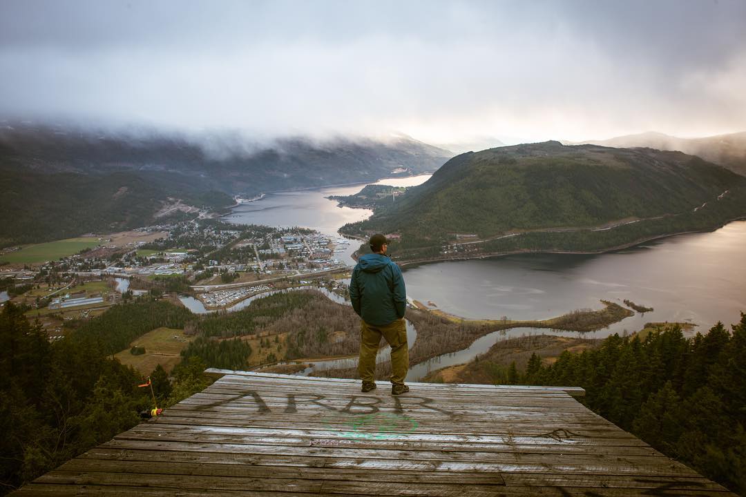 A man stands on a platform overlooking the lake below from the Sicamous Lookout