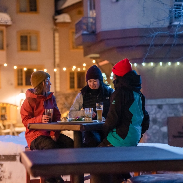 Three women sharing a beer outside