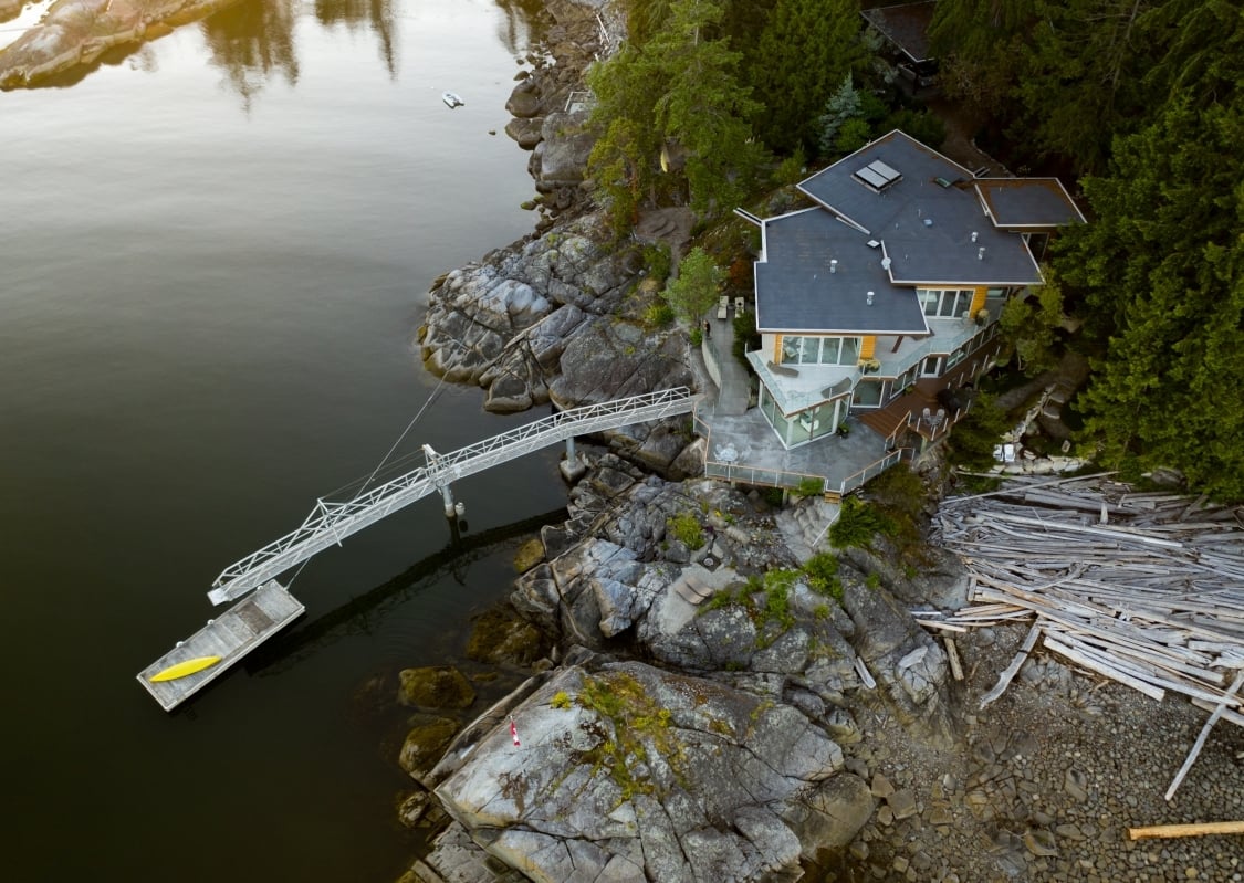 Aerial view of Pointhouse Suites, a house on the water with a large dock that extends out into the water.