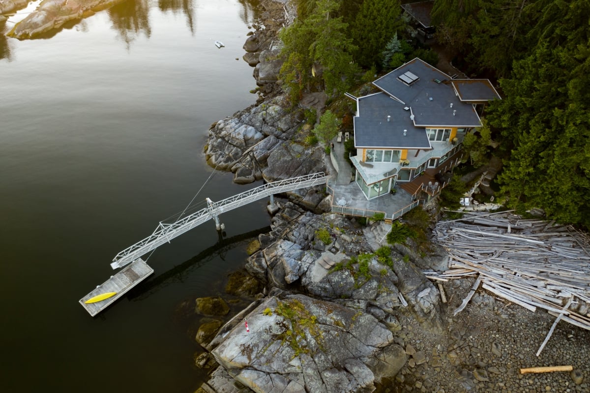 Aerial view of Pointhouse Suites, a house on the water with a large dock that extends out into the water.