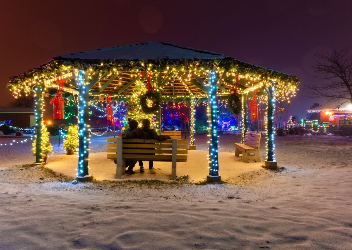 Couple sitting on a bench in a gazebo decorated with Christmas lights at the BC Wildlife Park in Kamloops | Peter Olsen