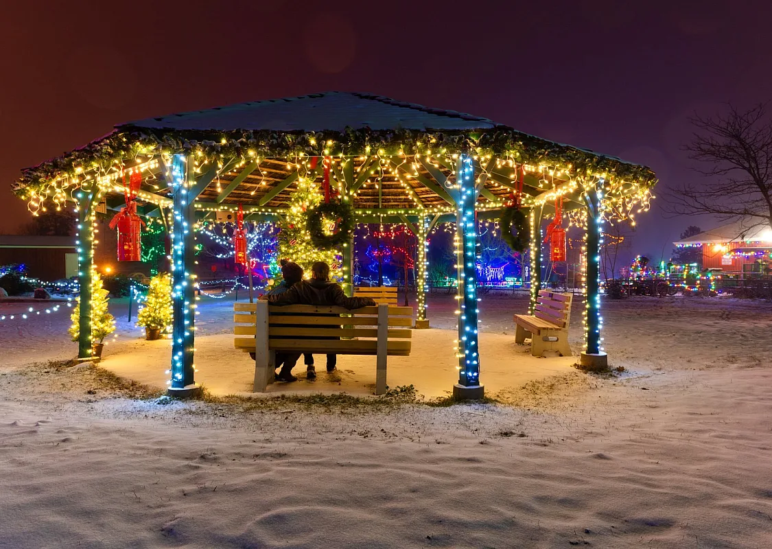 Ein Paar sitzt auf einer Bank in einem mit Weihnachtslichtern geschmückten Pavillon im BC Wildlife Park in Kamloops | Peter Olsen