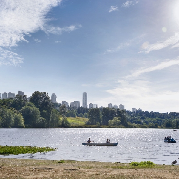 Zwei Personen paddeln an einem sonnigen Tag mit einem Kanu auf dem Deer Lake in Burnaby.