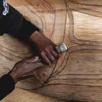 A person is holding a carving tool on a large piece of wood.