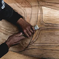 A person is holding a carving tool on a large piece of wood.