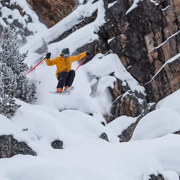 Una persona salta de una roca grande con esquís en Kicking Horse Mountain Resort.