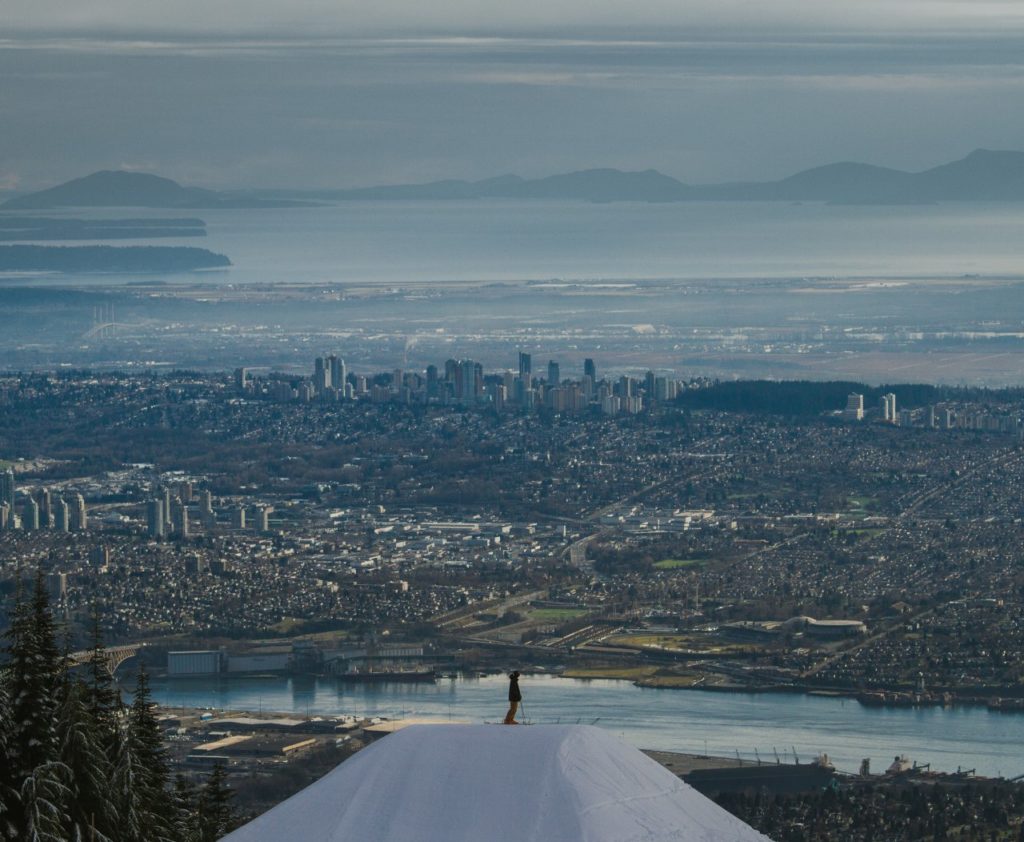 A person standing on top of a mountain overlooking a city
