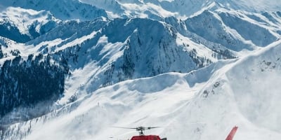 Group of heli-skiers being picked up by a helicopter near Mica Heli Skiing Lodge.