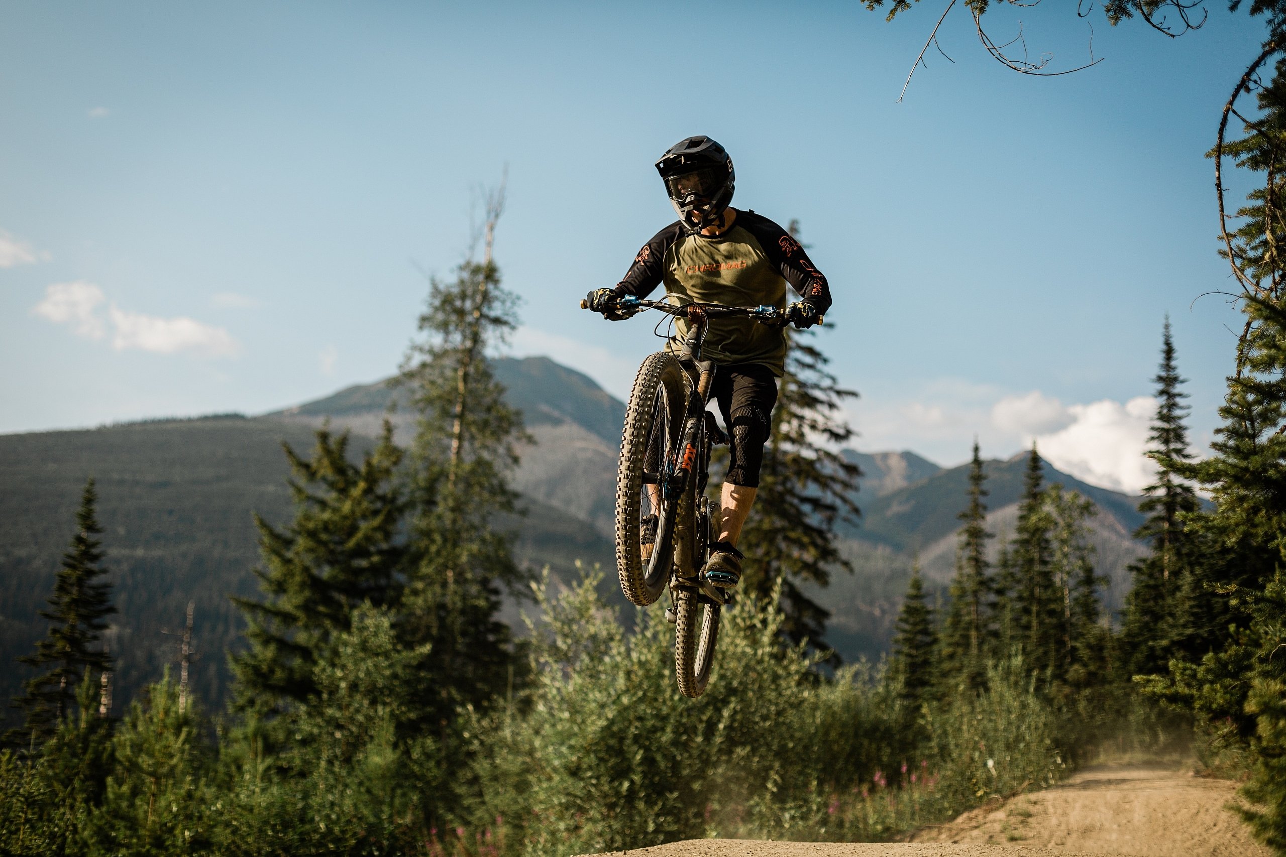 A biker wearing a full face helmet gets air as they hop over a jump.