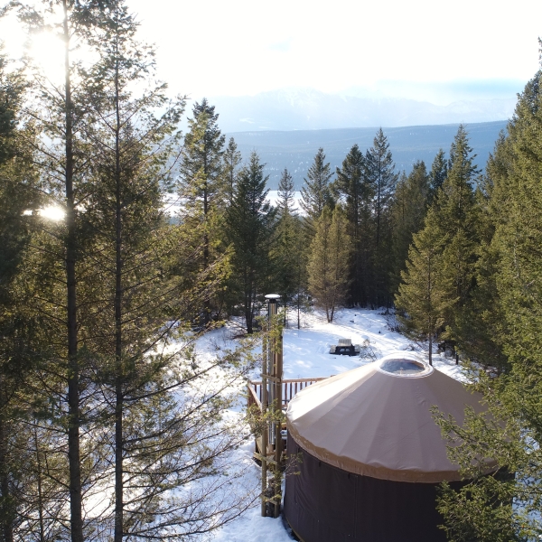 A Yurt surrounded by evergreen trees in the Kootenay Rockies. Snow covers the ground.