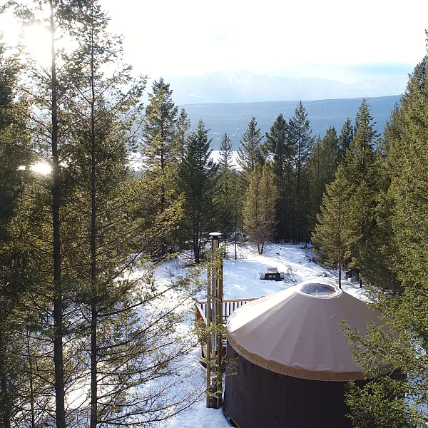 Eine Jurte umgeben von immergrünen Bäumen in den Kootenay Rockies. Schnee bedeckt den Boden.