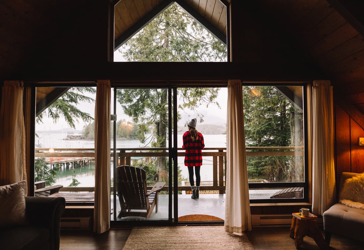 A women looks out a the ocean in Tofino from the deck of her a-frame cabin.