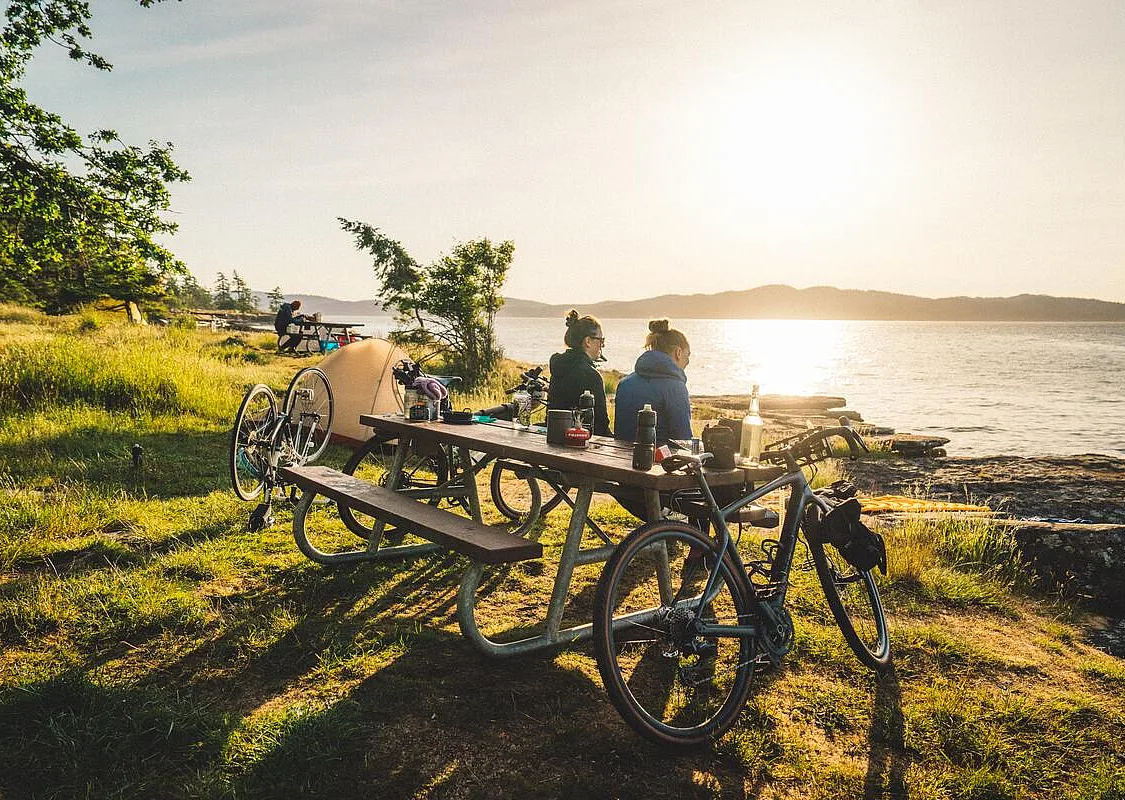 Two people sitting at a picnic table enjoying the ocean view at Ruckle Provincial Park during a bikepacking trip on Salt Spring Island.