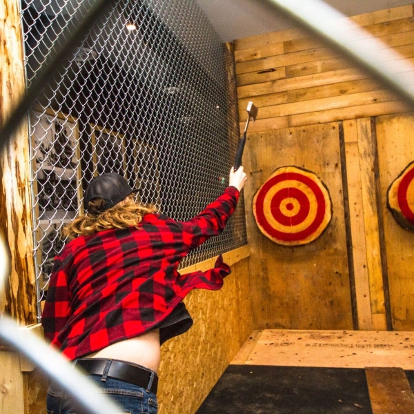 A person in red plaid shirt throws an axe at a bullseye in Revelstoke.