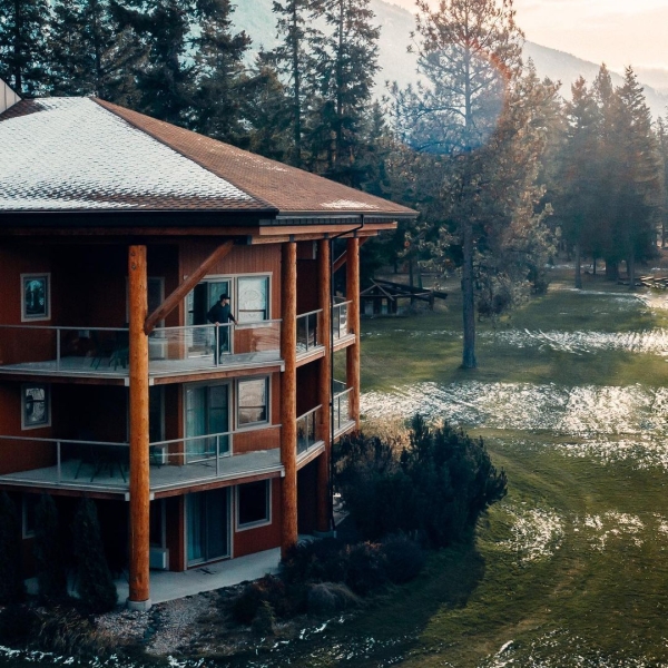 An outside view of Quaaout Lodge & Spa at Talking Rock Golf Resort. A light dusting of snow is on the roof and the grass field.