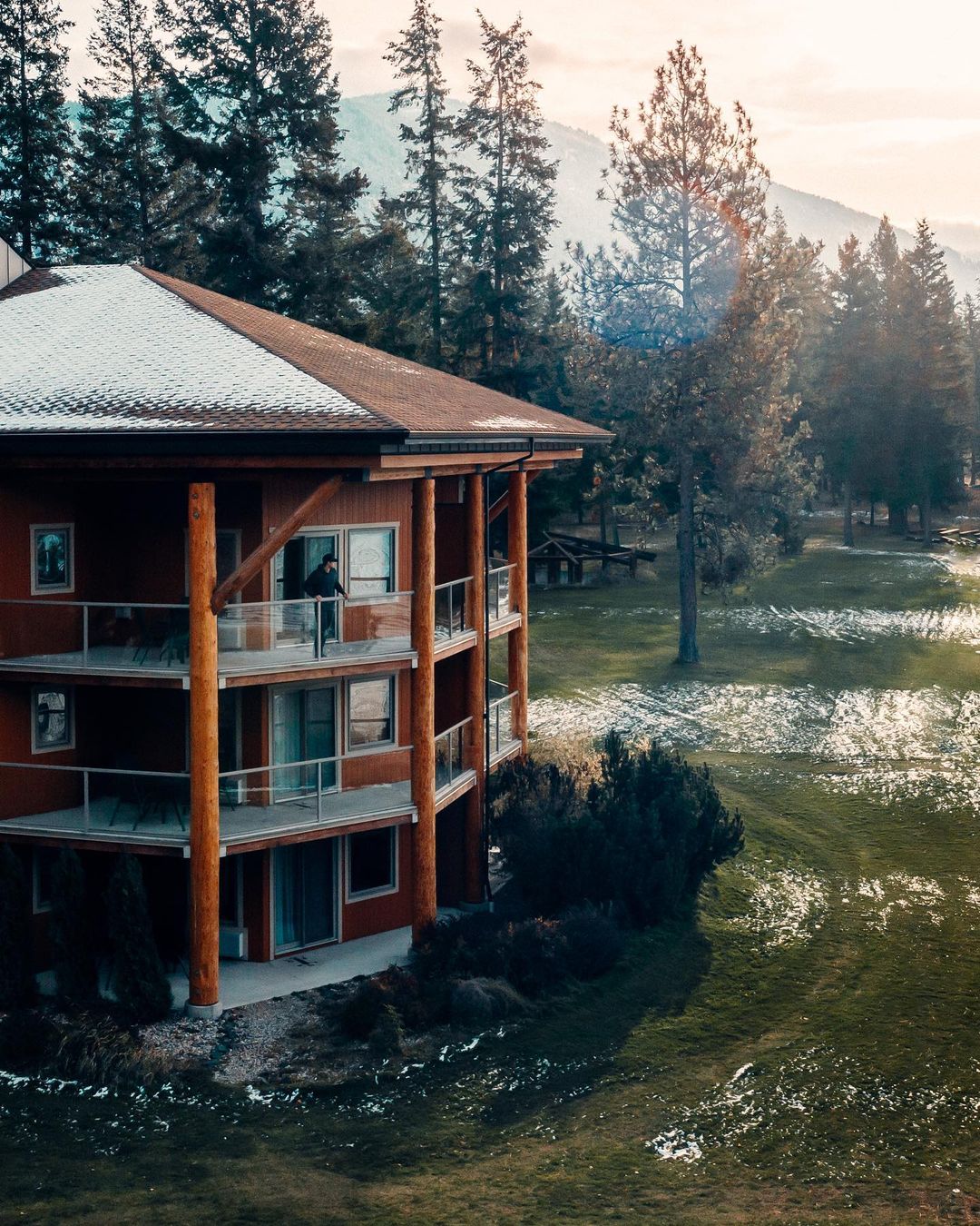 An outside view of Quaaout Lodge & Spa at Talking Rock Golf Resort. A light dusting of snow is on the roof and the grass field.
