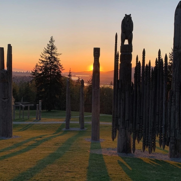 Sammlung von Totempfählen auf dem Burnaby Mountain, mit der Sonne, die dahinter untergeht