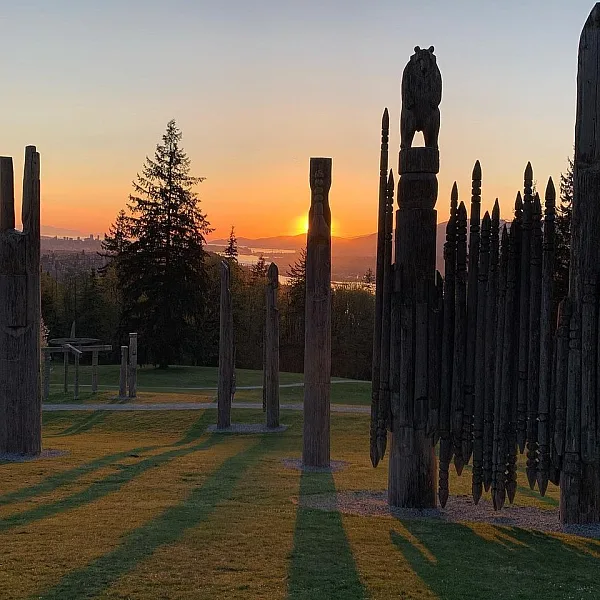 Sammlung von Totempfählen auf dem Burnaby Mountain, mit der Sonne, die dahinter untergeht